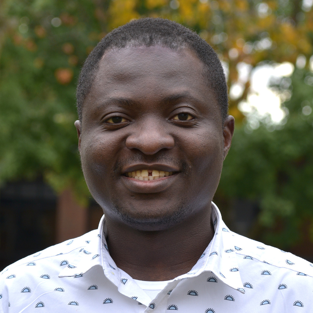 Male with dark features and warm smile in a light colored shirt