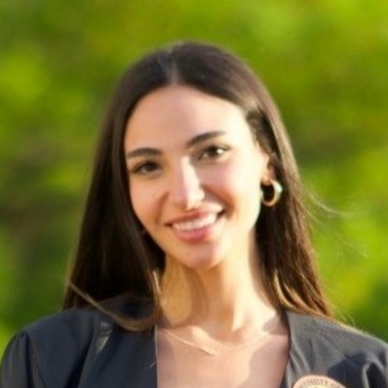 Young brunette with long hair wearing dark top with emblem