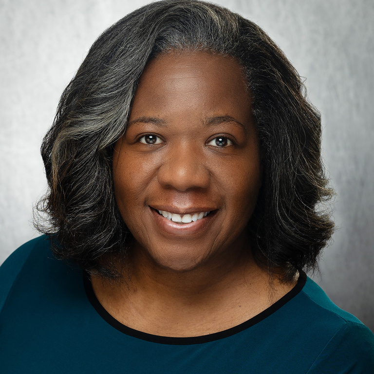 African American woman with dark hair wearing a grey-green top