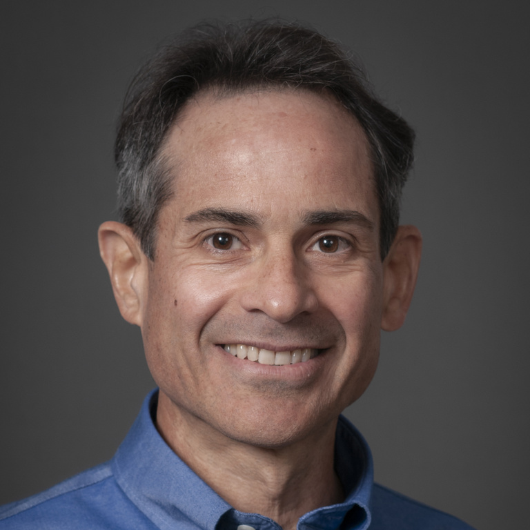 Photo of latino male with kind eyes, wearing blue collared shirt