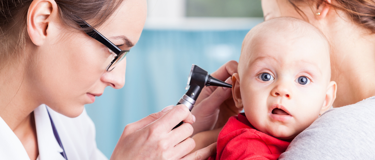 Doctor conducting ear exam on infant