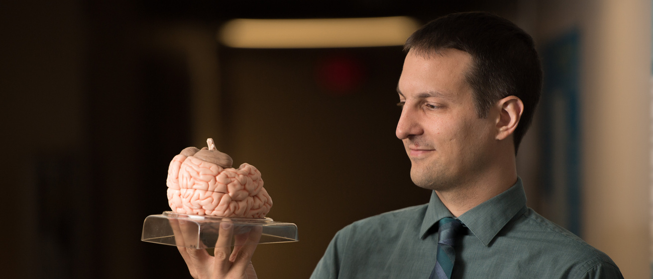 Photo of Aaron Boes and model of brain