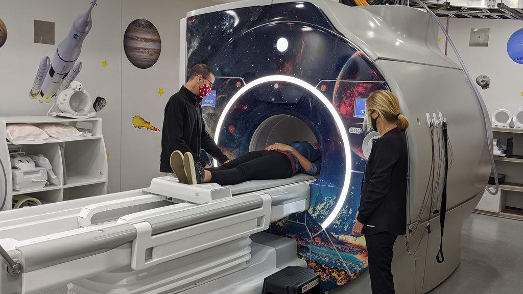 Photo of MRI machine with patient and techs assisting
